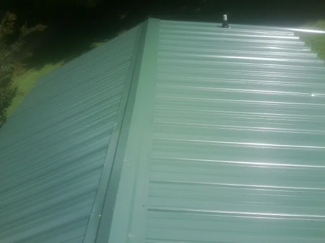 New green metal panels meeting at the ridge of a roof — Flat Roof Repair work by our crew in Bleiblerville