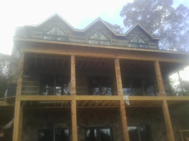 Dormers and porch framing on a large log home under construction — Roof Coating work by our crew in Bleiblerville