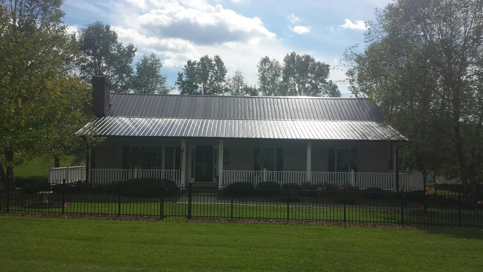 Gray metal roof on a brick ranch with a full width front porch — Gutter Guard Installation work by our crew in Bleiblerville