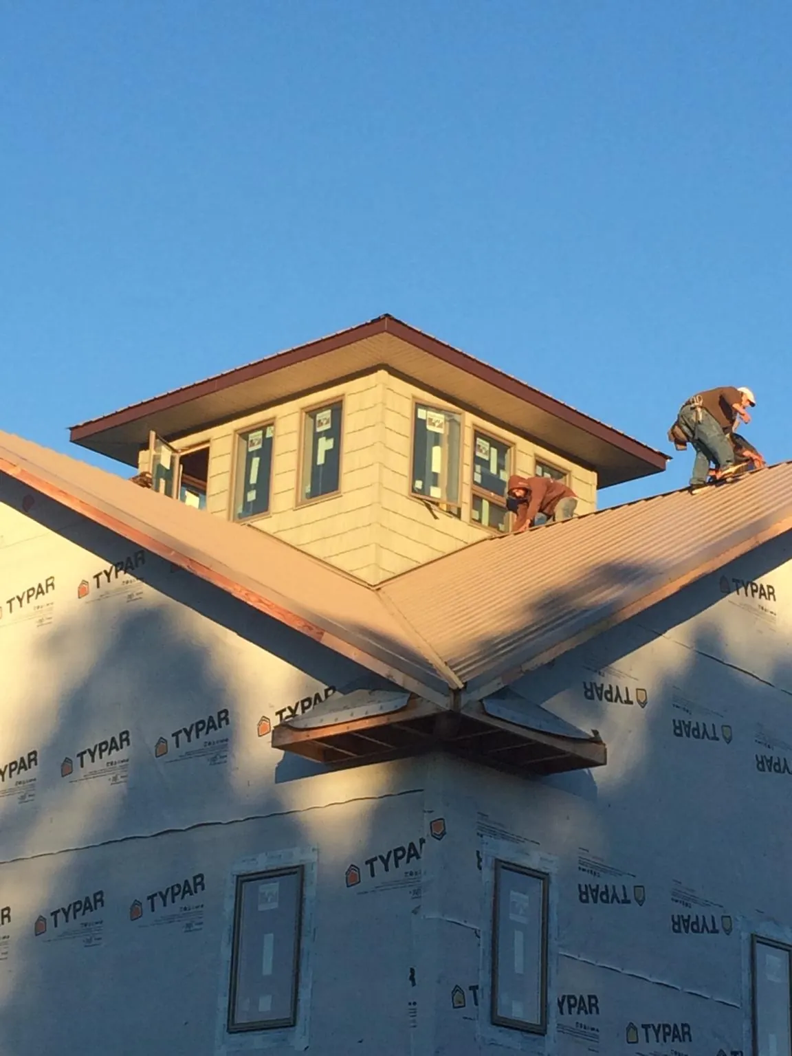 Roofers working around a rooftop cupola on a new metal roof at sunset — Roof Waterproofing in Bleiblerville by Roofing Brothers